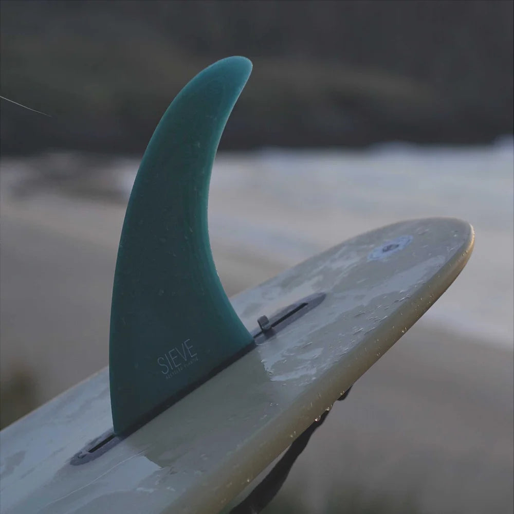 Sustainable Single Fin - 8'0 - color green blue screwed into a surfboard on the beach